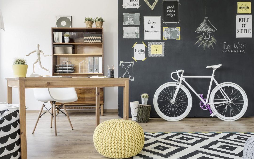 Modern home space with chalkboard wall, bike, pouffe, pattern carpet, desk and chair